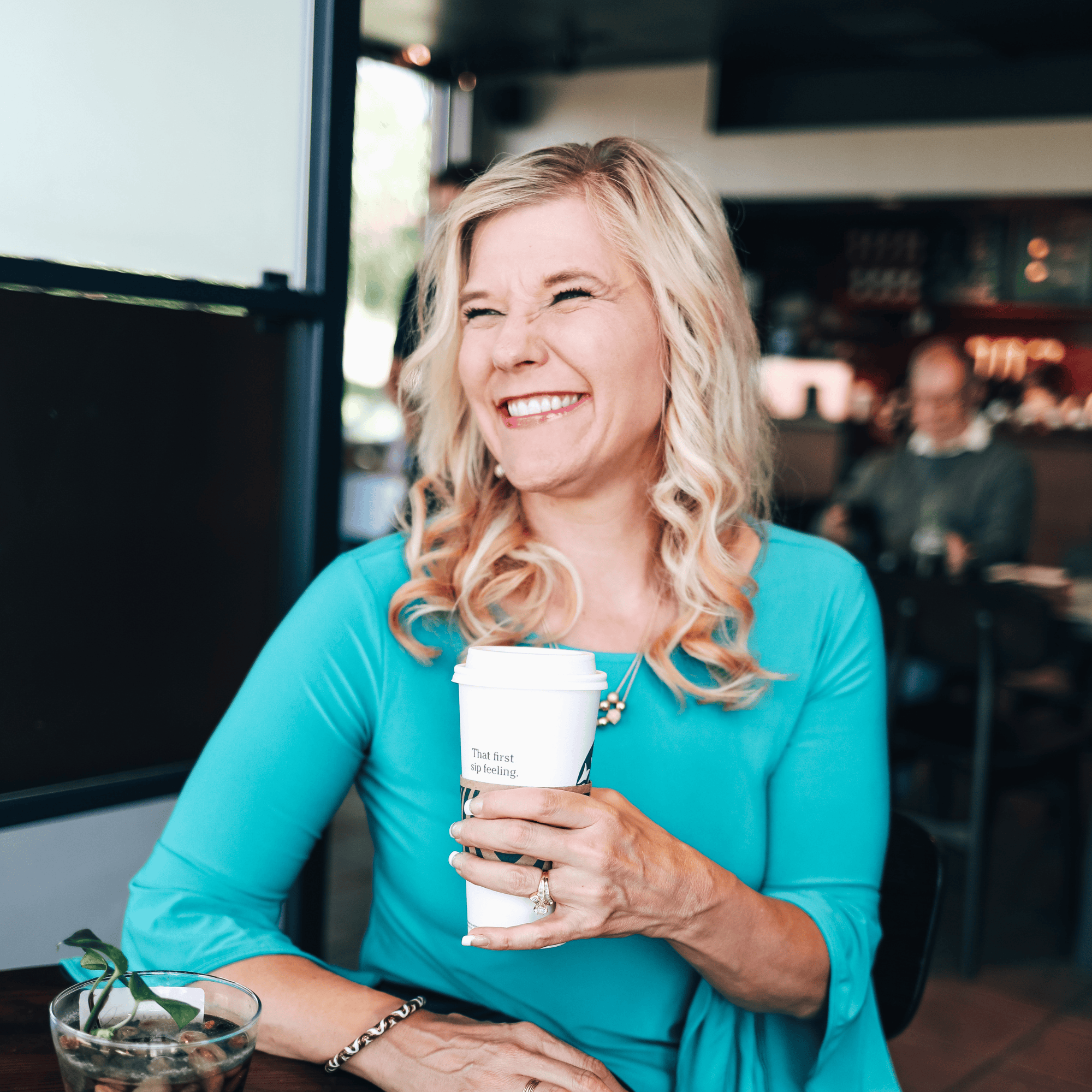 Catherine Smiling Holding a Coffee at a Coffee Shop